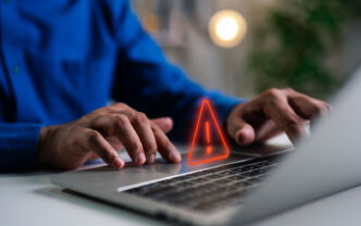 A person in a blue shirt sitting in front of a laptop trying to access