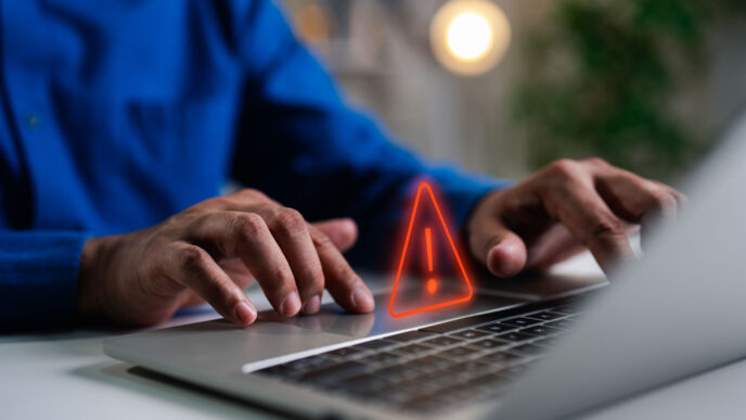 A person in a blue shirt sitting in front of a laptop trying to access